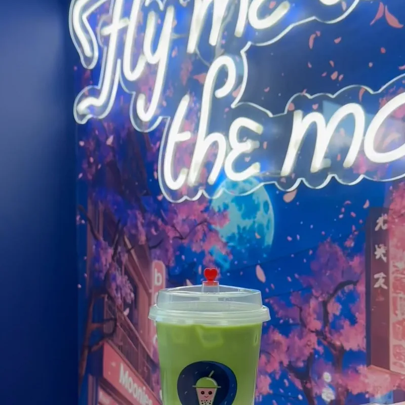 Green Moonies matcha in front of the Fly Me to the Moon wall